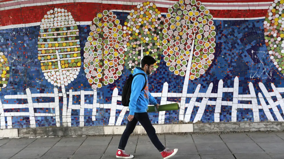 Un joven pasa frente a un mosaico decorativo en Teherán