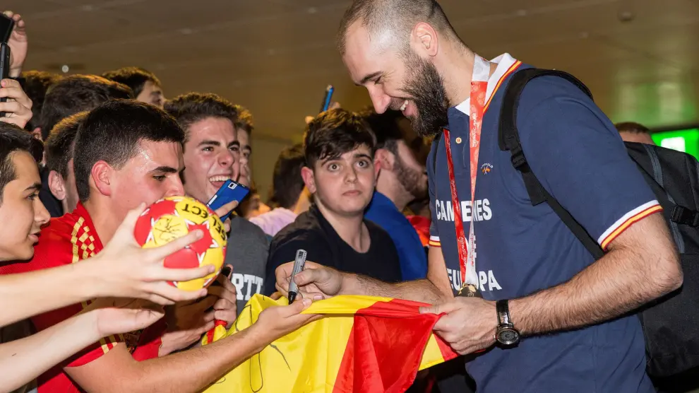 El jugador de la seleccion nacional de balonmano Joan Cañellas firma autógrafos a los aficionados a la llegada del combinado nacional al aeropuerto de Barajas, en Madrid. La selección de balonmano consiguió ayer su primer campeonato de Europa.