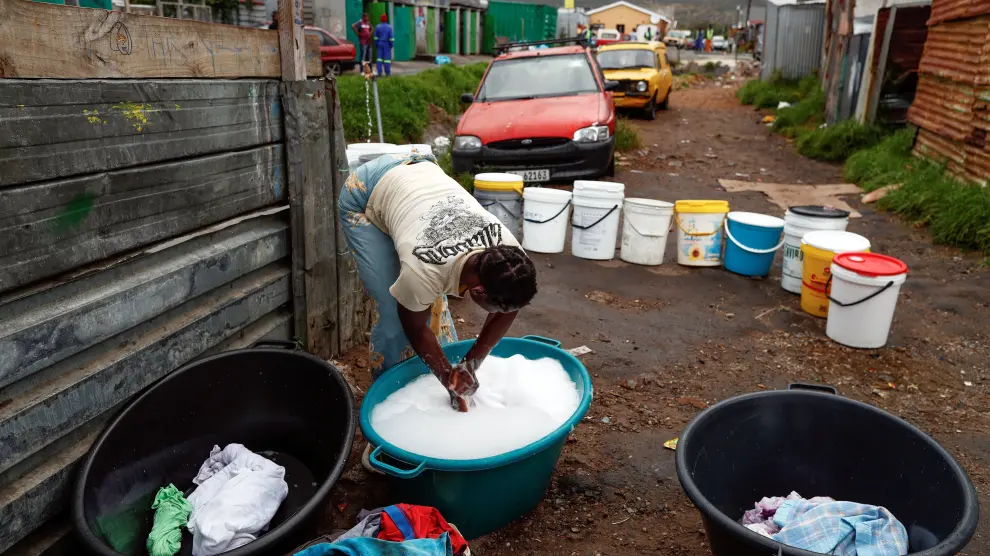 Una mujer lava su ropa con agua recolectada de un grifo comunitario