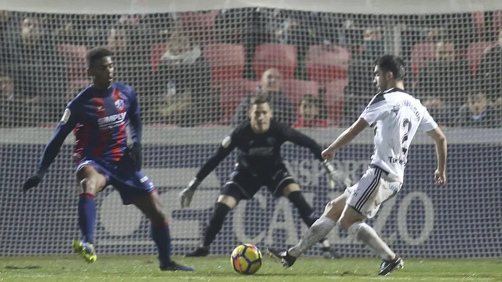 El portero Álex Remiro observa el intento de disparo de un jugador rival durante el Huesca-Oviedo mientras Jair intenta taparle.