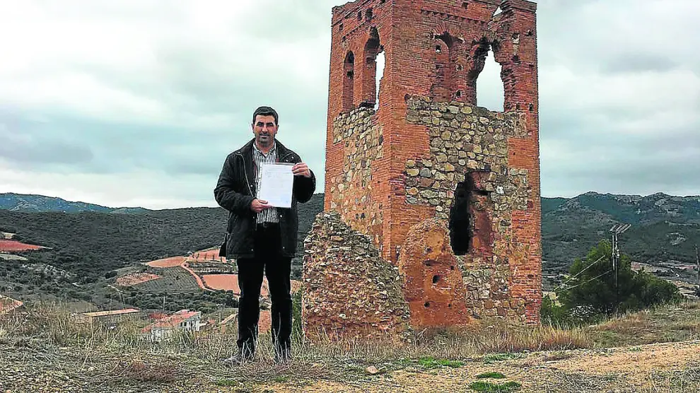 El alcalde de Cosuenda, Óscar Lorente, muestra las escrituras del terreno, junto a la torre.