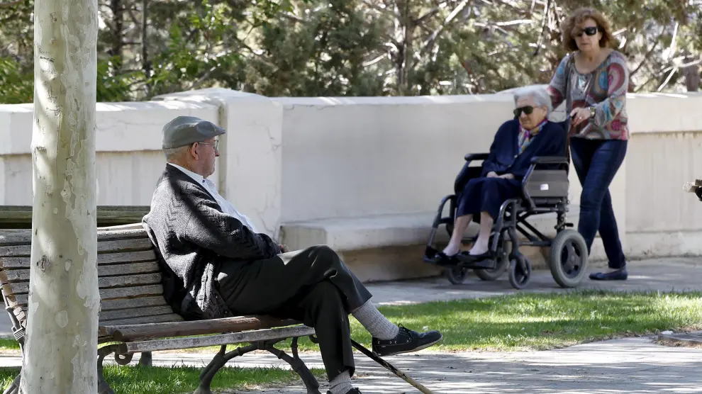 Imagen de un jubilado en el parque de los Fueros de Teruel, donde una mujer pasea a su vez a una anciana.