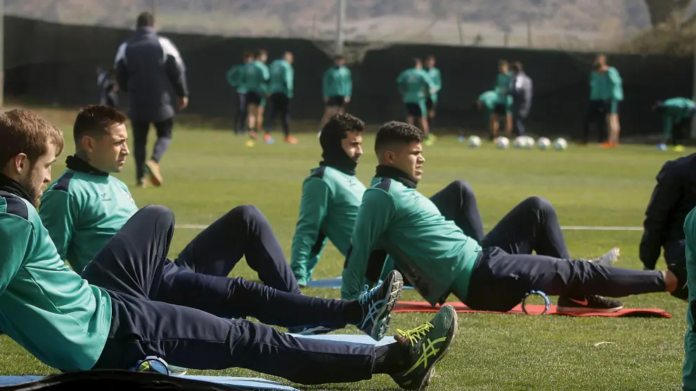 Algunos jugadores del Huesca realizan ejercicios de estiramiento durante un entrenamiento.