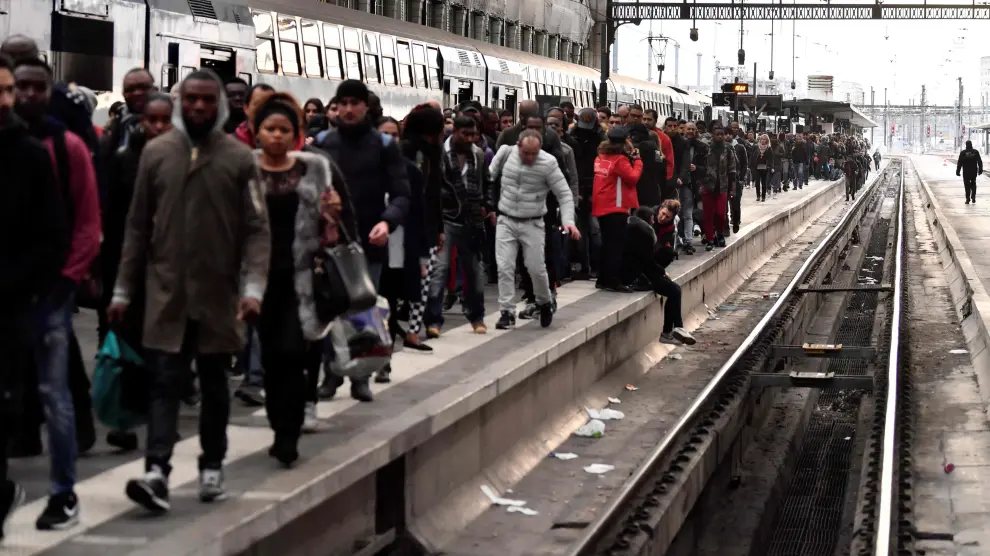 Los pasajeros esperan sentados o caminando por las vías en el primer día de huelga ferroviaria