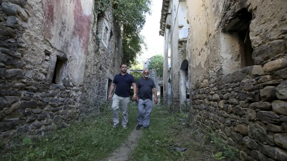 El alcalde de Fiscal, Manuel Larrosa, y Jesús Garcés, uno de los afectados, en las calles de Jánovas, con las casas en ruinas