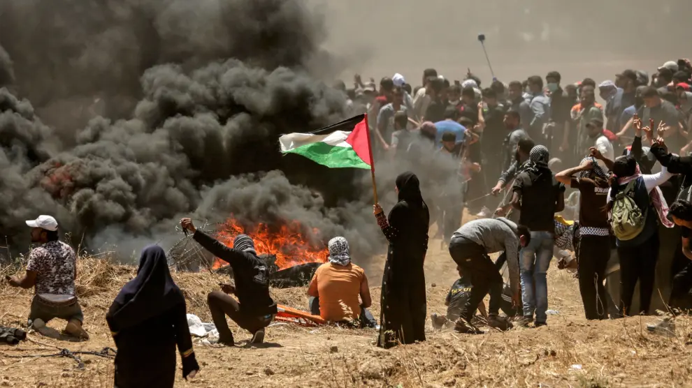 Una mujer palestina sostiene una bandera en medio de las protestas