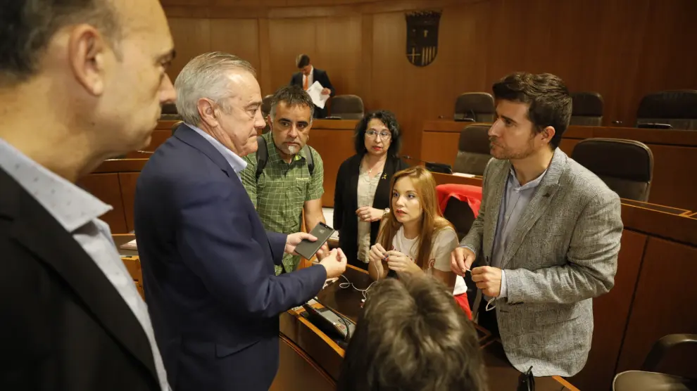 Nacho Escartín, a la derecha, habla con el socialista Javier Sada antes de comenzar el pleno de este jueves