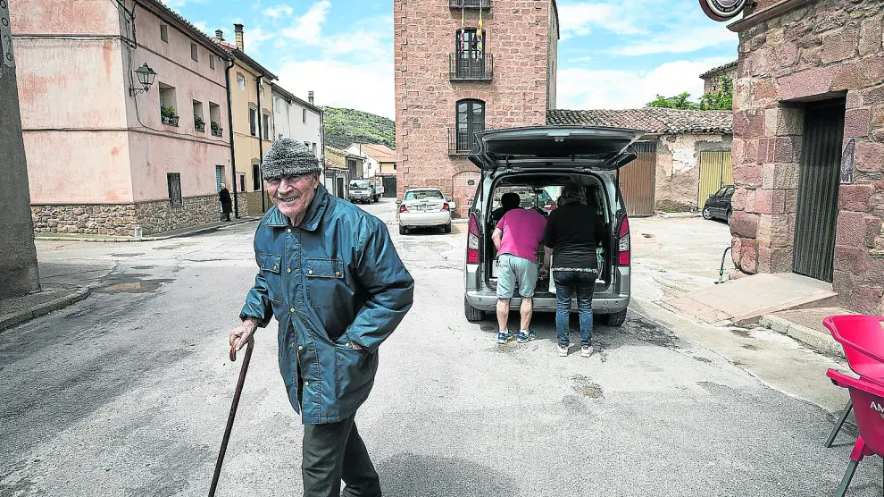 Un vecino de Villar del Salz sonríe a cámara con el ayuntamiento (el más estrecho de la provincia de Teruel) al fondo.