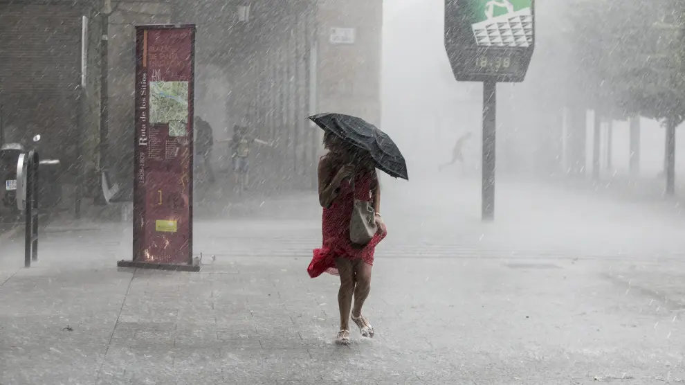 Una mujer trata de resguardarse de la lluvia en el Paseo de la Independencia
