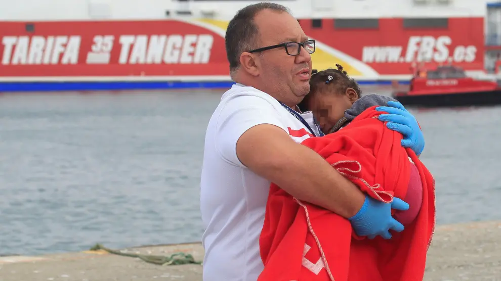 Un voluntario de Cruz Roja auxilia a una niña recién llegada a Tarifa