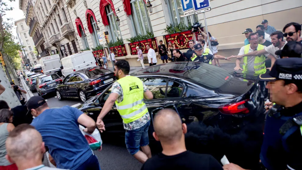 Un grupo de taxistas increpando a un coche frente al hotel Palace de Barcelona.