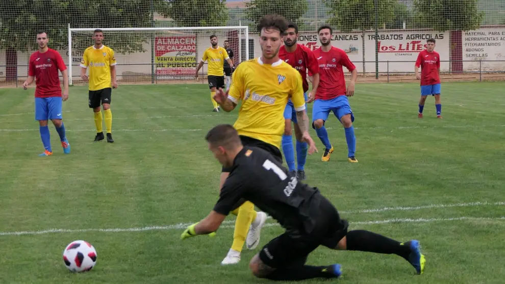El jugador del Ejea Héctor Otín intenta salvar al portero del Cariñena en un partido amistoso de pretemporada
