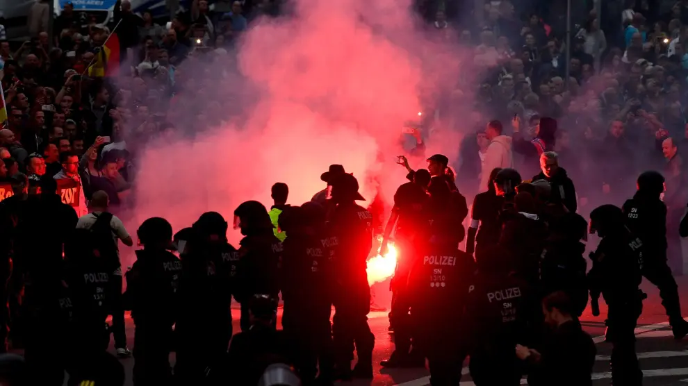 Manifestantes de derecha prenden bengalas mientras enfrentan a la policía antidisturbios en Chemnitz (Alemania).