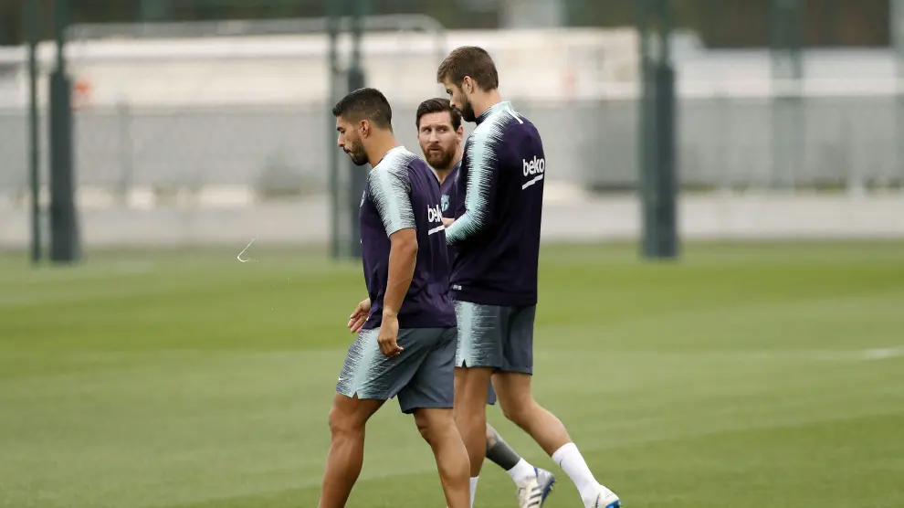 Leo Messi dialoga con Piqué, en presencia de Luis Suárez, durante el entrenamiento que el Barcelona ha completado este sábado.