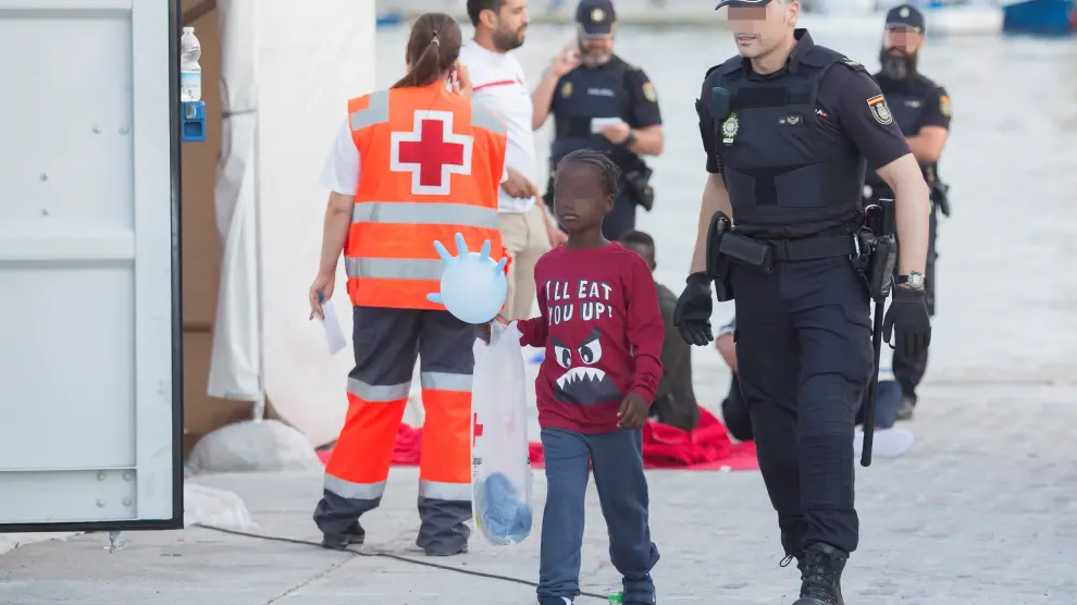 Uno de los menores rescatados junto a un Policía Nacional en el puerto de Málaga