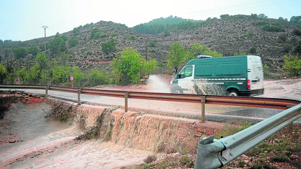 Una torrentera anega y cruza la carretera N-330, también cortada por la caída de rocas, entre Teruel y Villastar.