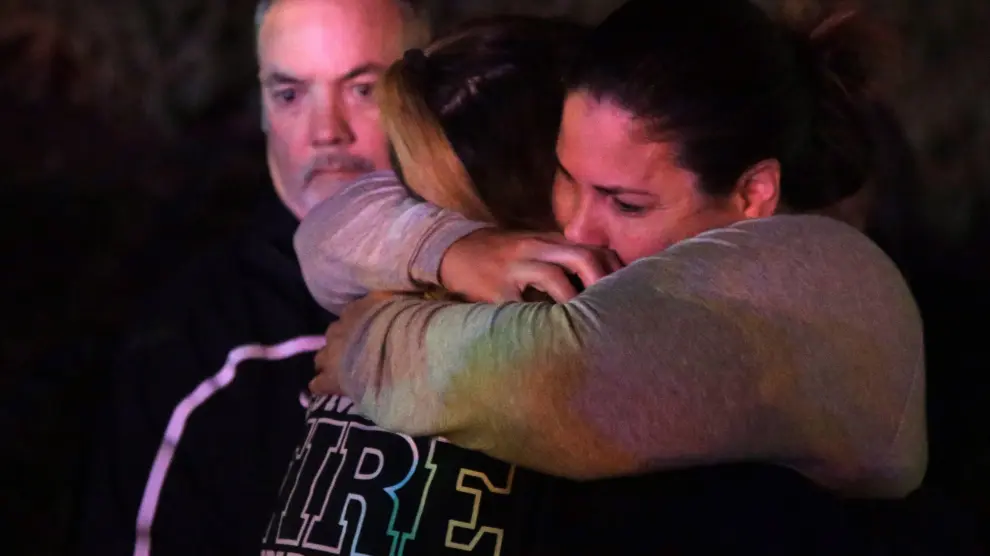 Una mujer que huyó del lugar del tiroteo en un bar de California abraza a sus familiares.