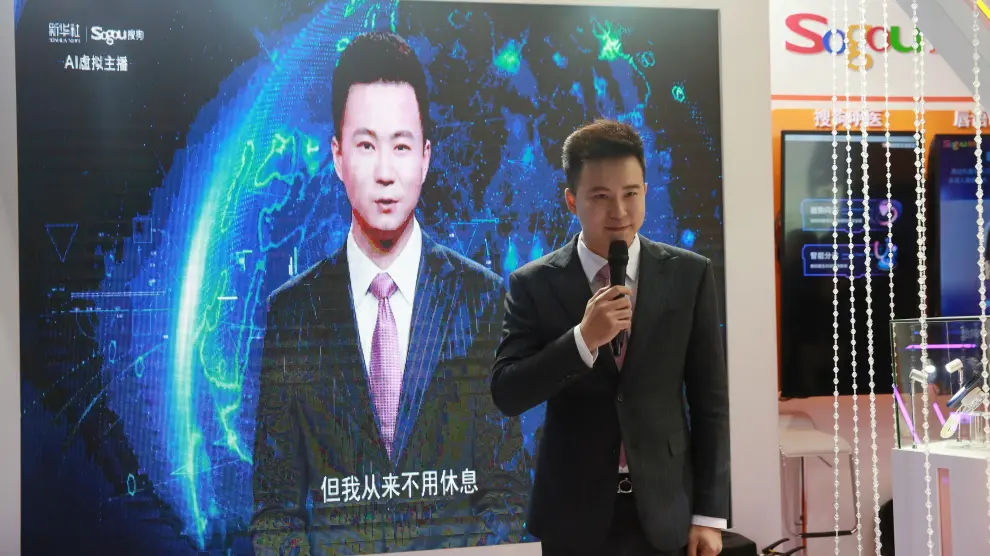 El periodista chino Qiu Hao, ante una pantalla con un presentador virtual basado en su imagen.