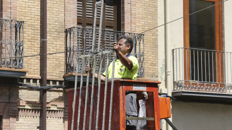 Un operario de las brigadas municipales coloca la iluminación de las Fiestas de San Lorenzo