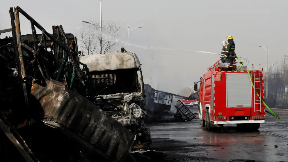 Bomberos apagando el fuego de uno de los camiones incendiados.