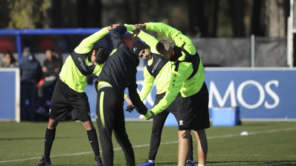 Cuatro jugadores de la SD Huesca realizan estiramientos en un entrenamiento.