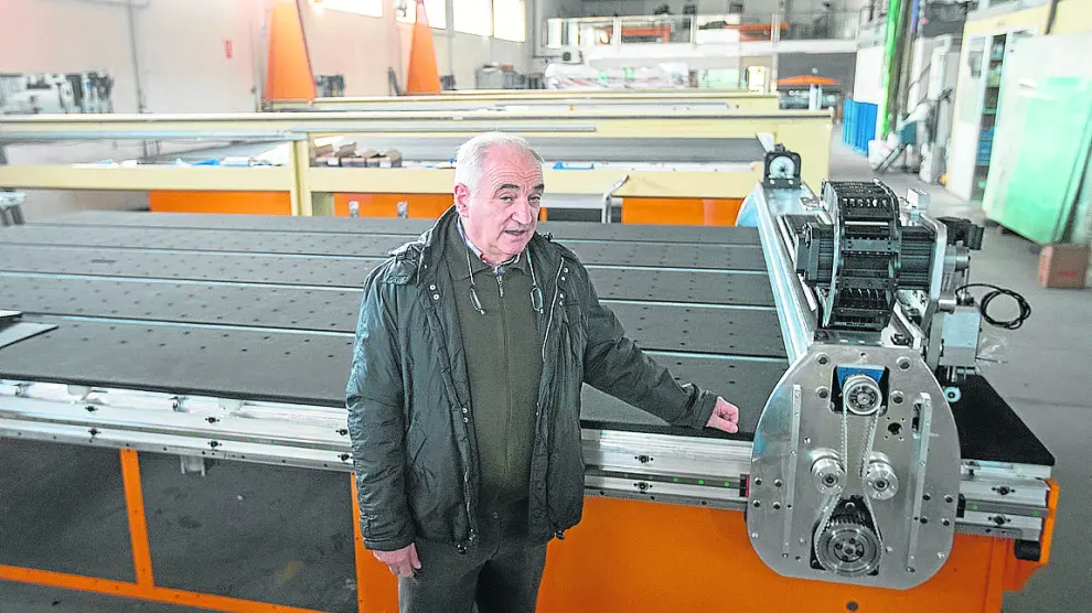 Miguel Tomás, junto a una de las máquinas de corte de vidrio que fabrica en Rubielos de Mora.