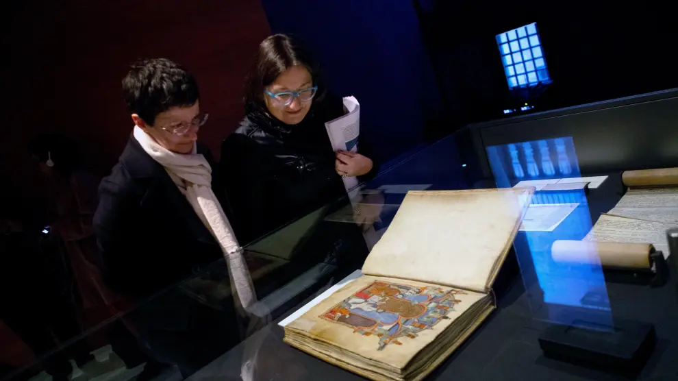 Dos visitantes observan el Gran Libro de los Feudos, una de las joyas del Archivo de la Corona de Aragón que se exhiben en Barcelona.