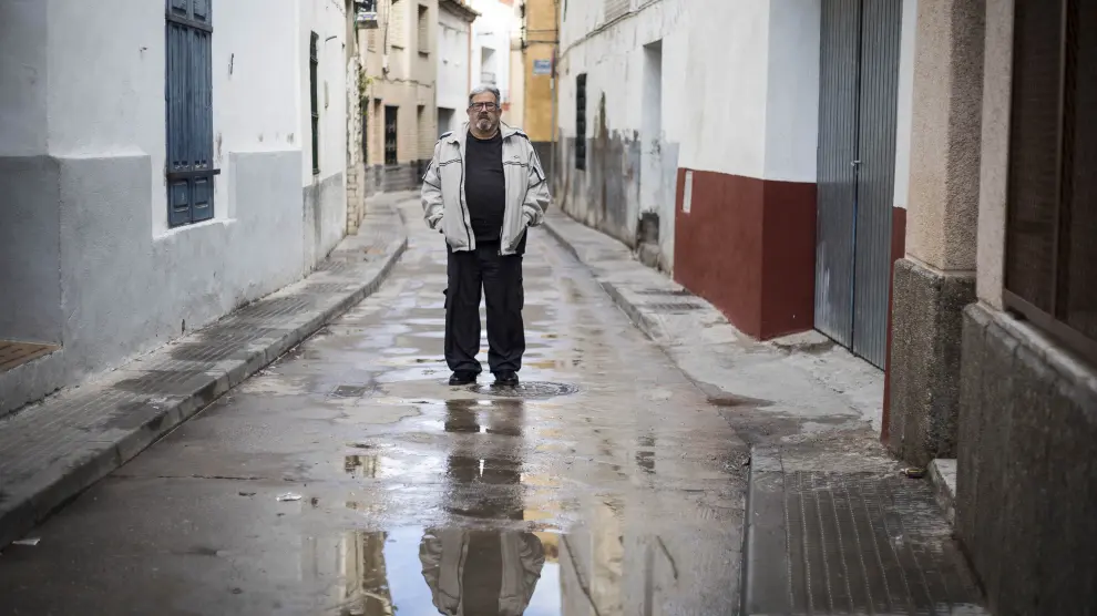 El cocinero y escritor local Jesús Aznar (con su reflejo en el agua) posa en una estrecha calle de Lumpiaque.