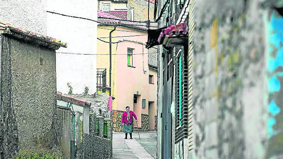 Una vecina pasea por una calle de Lagueruela al atardecer.