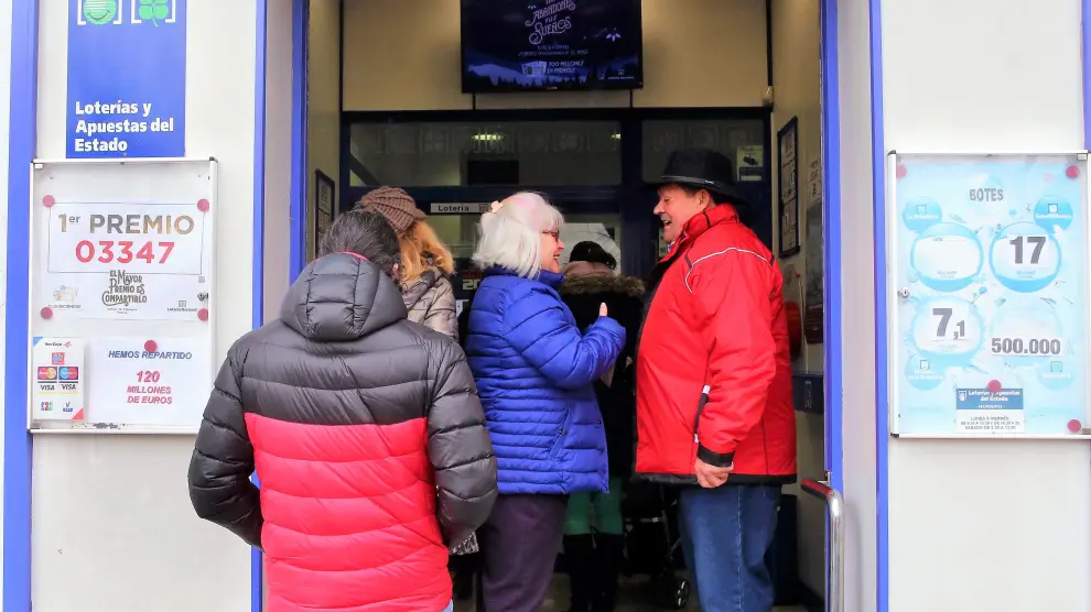 Clientes esperando para comprar lotería ante la puerta de la administración de la avenida Juan XXIII de Huesca.