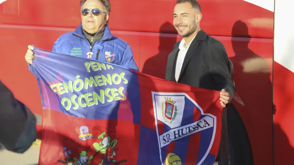 Ferreiro sujeta una bandera con el escudo de la SD Huesca, antes de partir hacia Leganés.