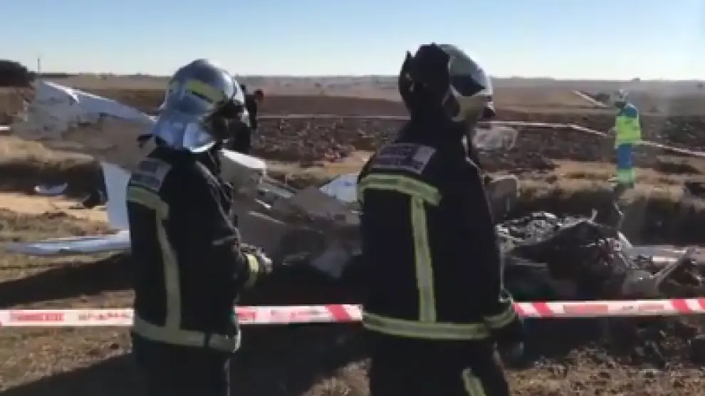 Dos bomberos ante los restos de la aeronave siniestrada.