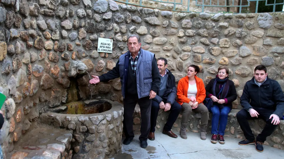Vecinos de Plasencia del Monte junto a la fuente con el cartel 'Agua no apta para el consumo'
