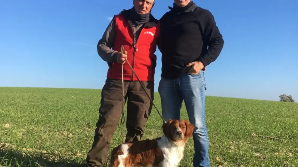 El criador Julián Oliván, de rojo, y Emiliano Rodríguez, el conductor del perro, junto a Colungo del Somontano.
