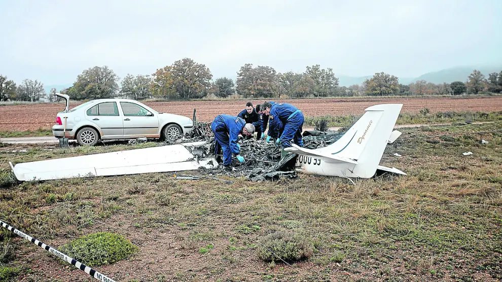 Agentes de la Policía, durante la investigación de los restos de la avioneta calcinada.