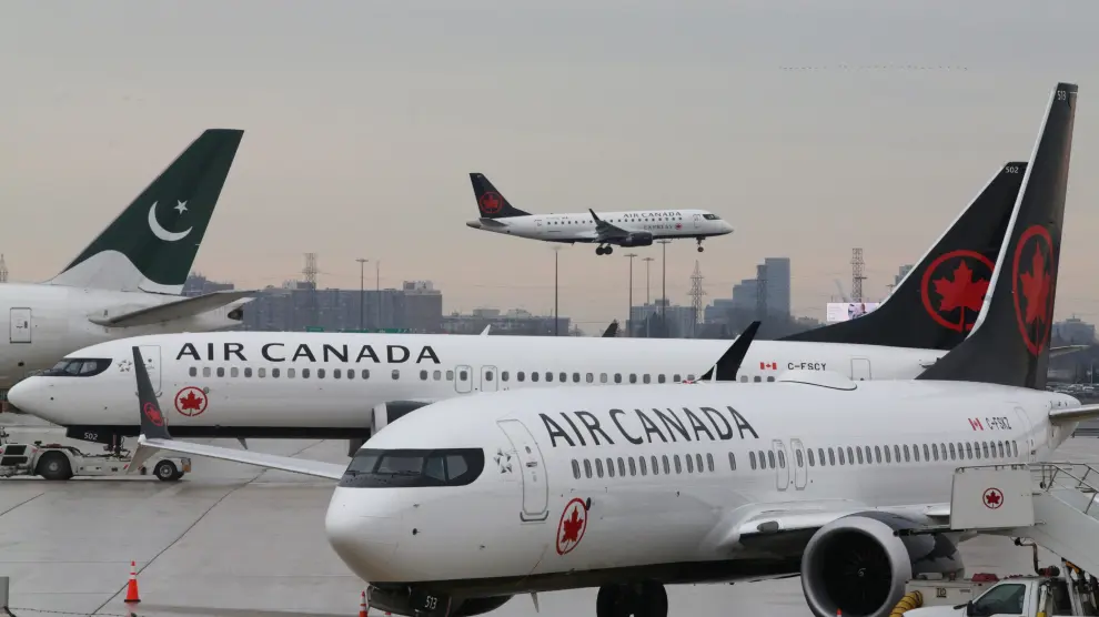 Two Air Canada Boeing 737 MAX 8 aircrafts are seen on the ground as Air Canada Embraer aircraft flies in the background at Toronto Pearson International Airport in Toronto, Ontario, Canada, March 13, 2019. REUTERS/Chris Helgren [[[REUTERS VOCENTO]]] ETHIOPIA-AIRPLANE/CANADA