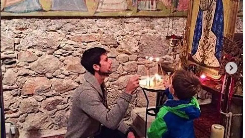 Novac Djokovic junto con su hijo Stefan poniendo ambos una vela ante un icono de la Virgen María