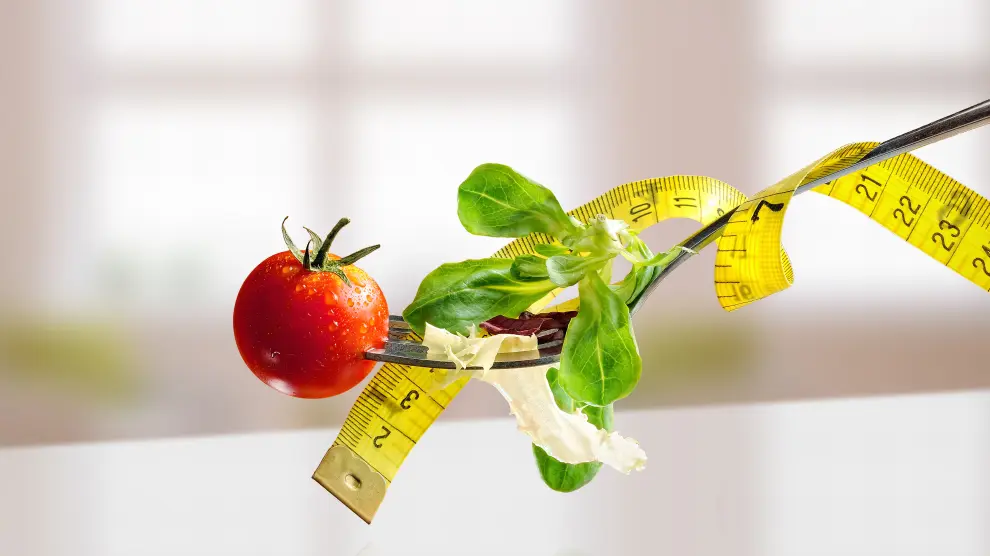 Salad with lettuce and tomato on a metal fork with tape on white table and windows background. Concept of healthy diet and nutrition. Front view, Horizontal composition.