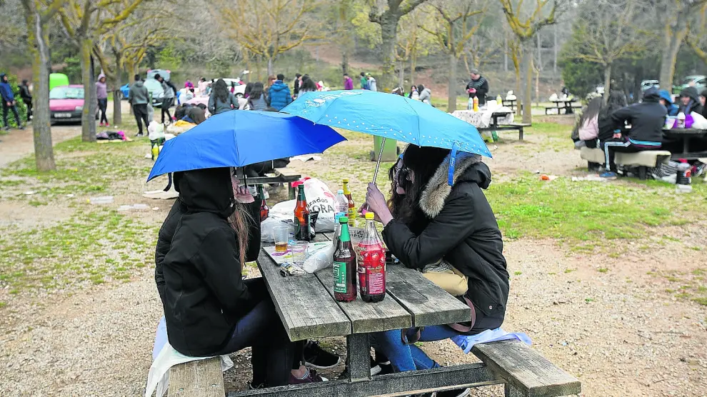 La lluvia obligó a sacar el paraguas en la Fuente Cerrada, el paraje preferido por los turistas para celebrar la fiesta.