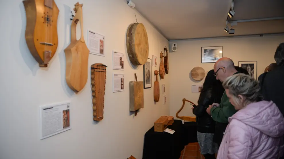 Unos visitantes observan los instrumentos musicales, piezas modernas de modelos antiguos, de la exposicion temporal en el Museo de Albarracín.