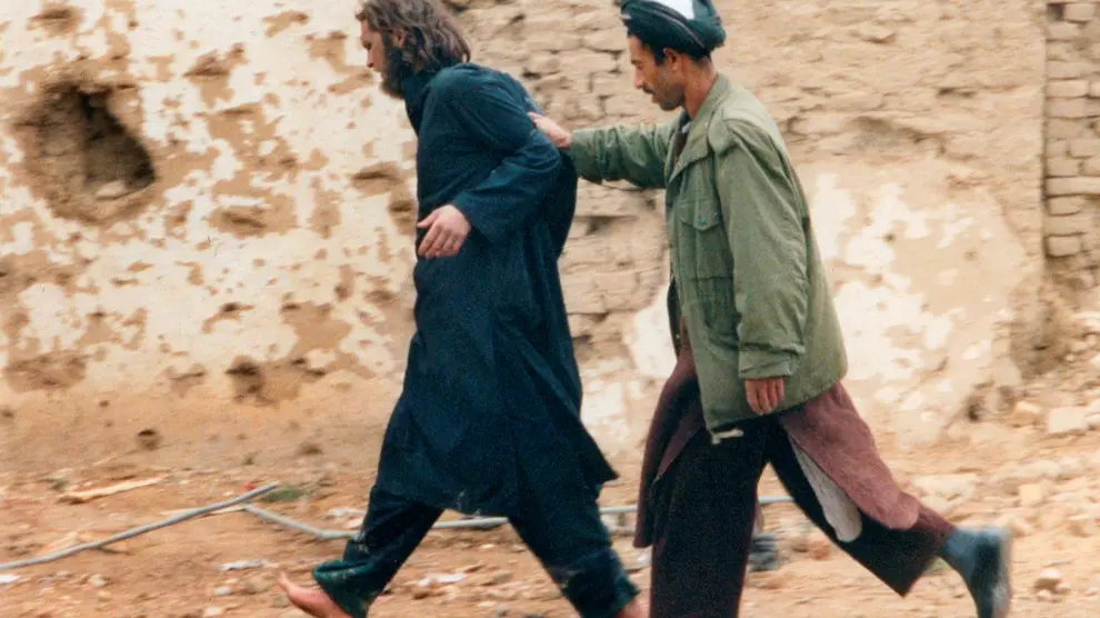 FILE PHOTO: U.S.-born John Walker Lindh (L) is led away by a Northern Alliance soldier after he was captured among al Qaeda and Taliban prisoners following an uprising at the Fort Qali-i-Janghi prison near Mazar-i-Sharif December 1, 2001 REUTERS/STR/File Photo [[[REUTERS VOCENTO]]] USA-CRIME/LINDH