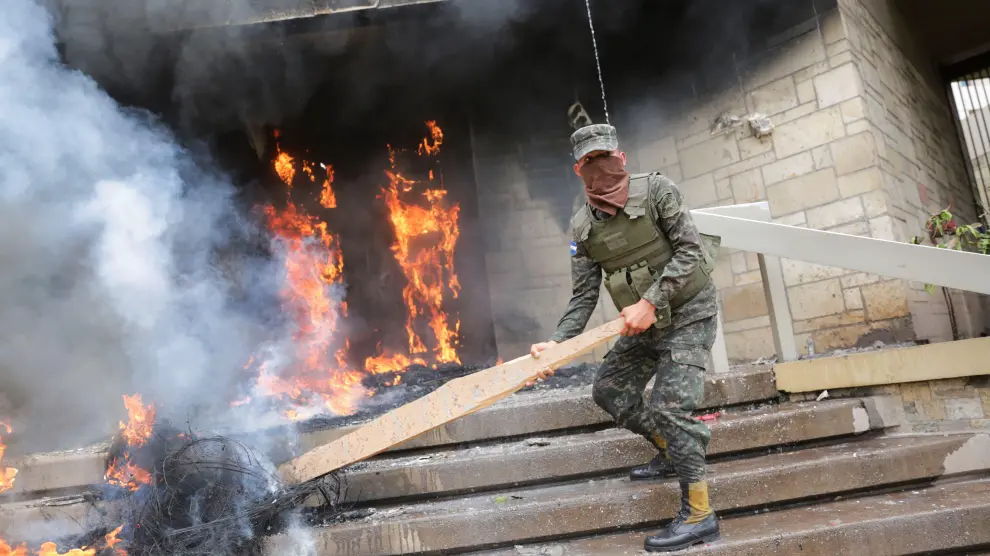 Un soldado intenta apagar los neumáticos en llamas en una de las puertas de acceso a la Embajada de Estados Unidos.