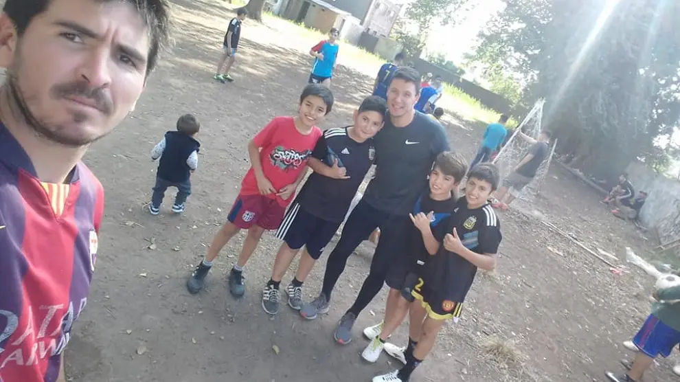 Damian Musto, al fondo, con varios de los niños con los que jugó a fútbol.