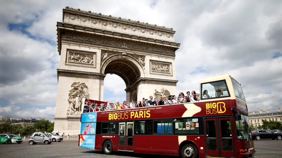 FILE PHOTO: Tourists ride in an open-air double-decker bus past the Arc de Triomphe in Paris, France, May 30, 2017. REUTERS/Charles Platiau/File Photo [[[REUTERS VOCENTO]]] FRANCE-TOURISM/