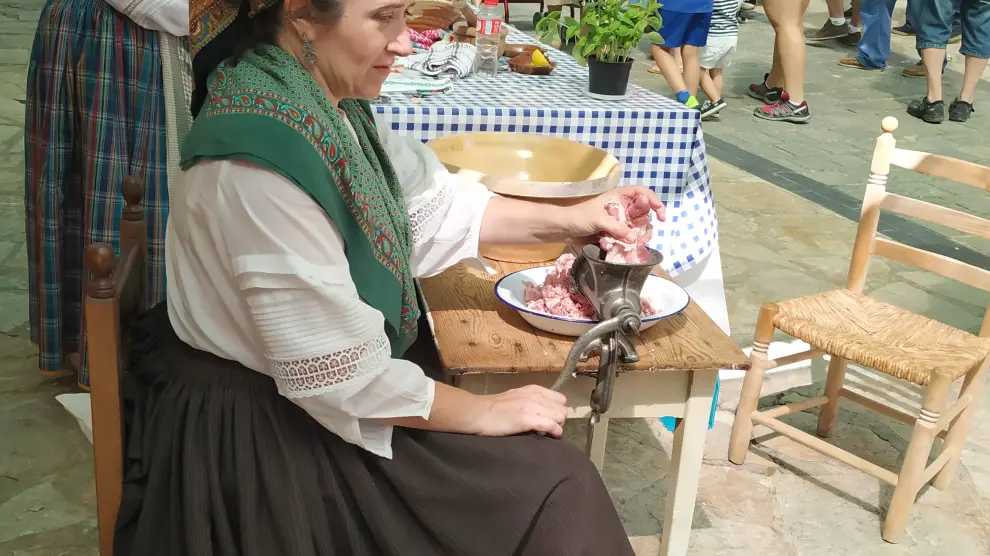 Una mujer, con la capoladora de la carne, en la feria de oficios antiguos de Lituénigo