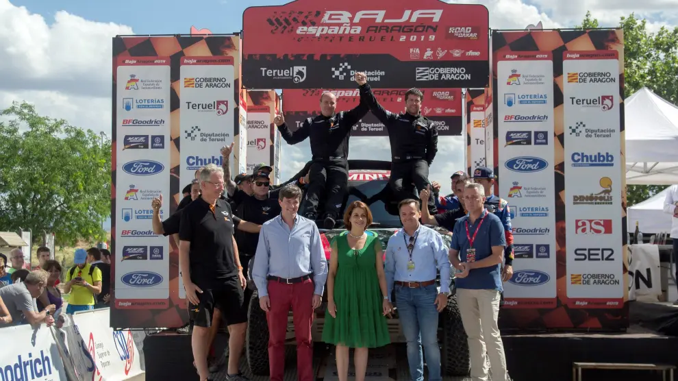 El piloto argentino Orlando Terranova (fondo-d) y su copiloto y compatriota Ronnie Graue (fondo-i), ambos del equipo X-Raid Mini JCW Team, celebran este sábado tras conseguir la victoria en el Rally Baja Aragón que disputa en la provincia de Teruel.