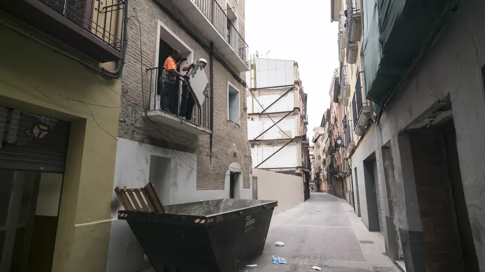 Un obrero arroja al contenedor basura y trastos de la casa okupa de Agustina de Aragón 26.