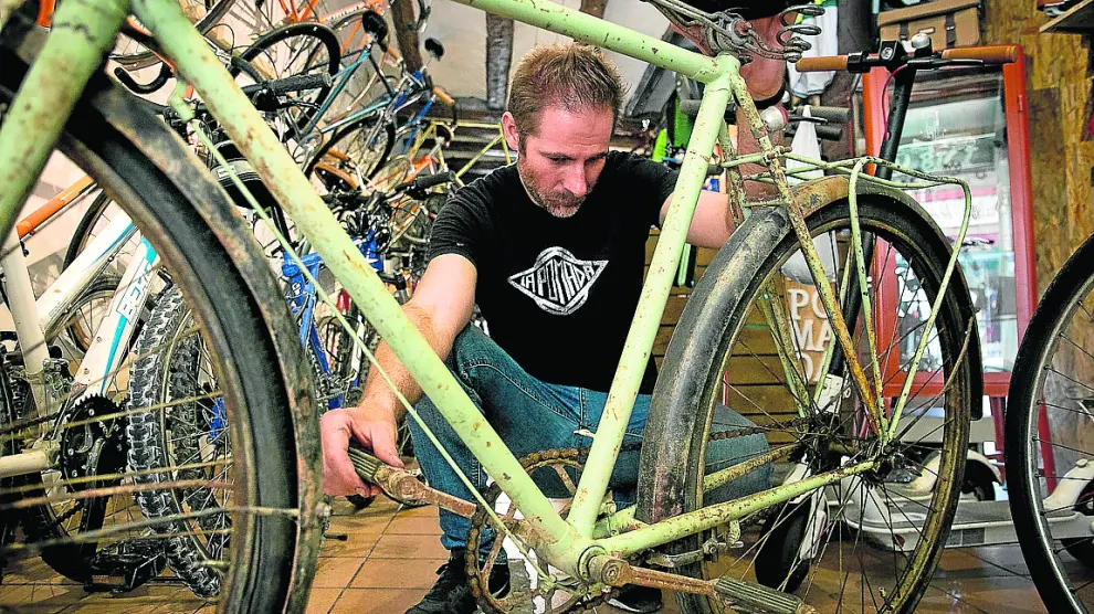 José Manuel Tomé, de La Pomada Bikes, inspecciona una bicicleta para rehabilitarla.