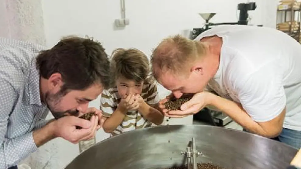 Luis Fernández, de la marca zaragozana Papa Largo, oliendo café con su hijo y el experto tostador Guido.