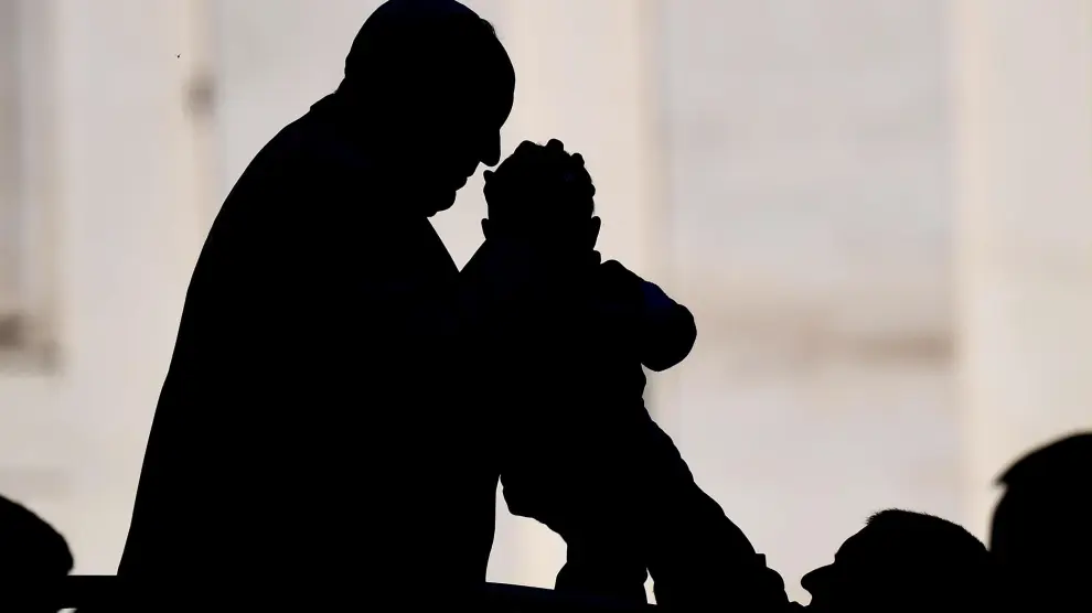 El Papa besa a un bebé alzado por su padre en una audiencia reciente.